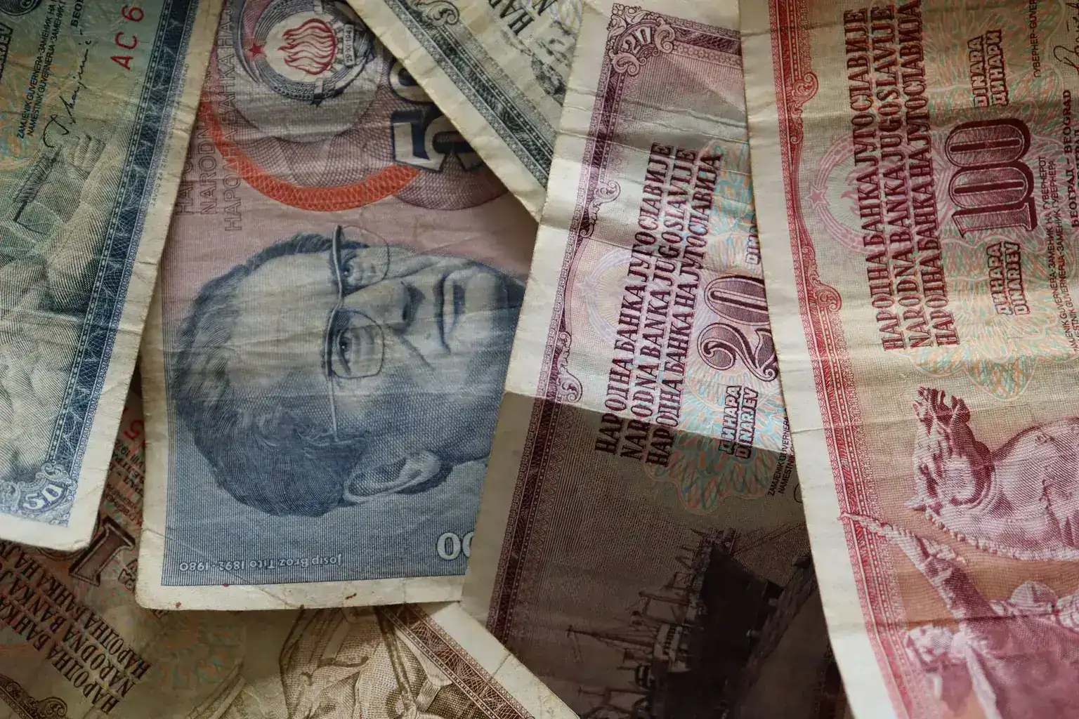 Close view of overlapping worn banknotes showing portraits, printed text, and fine line work