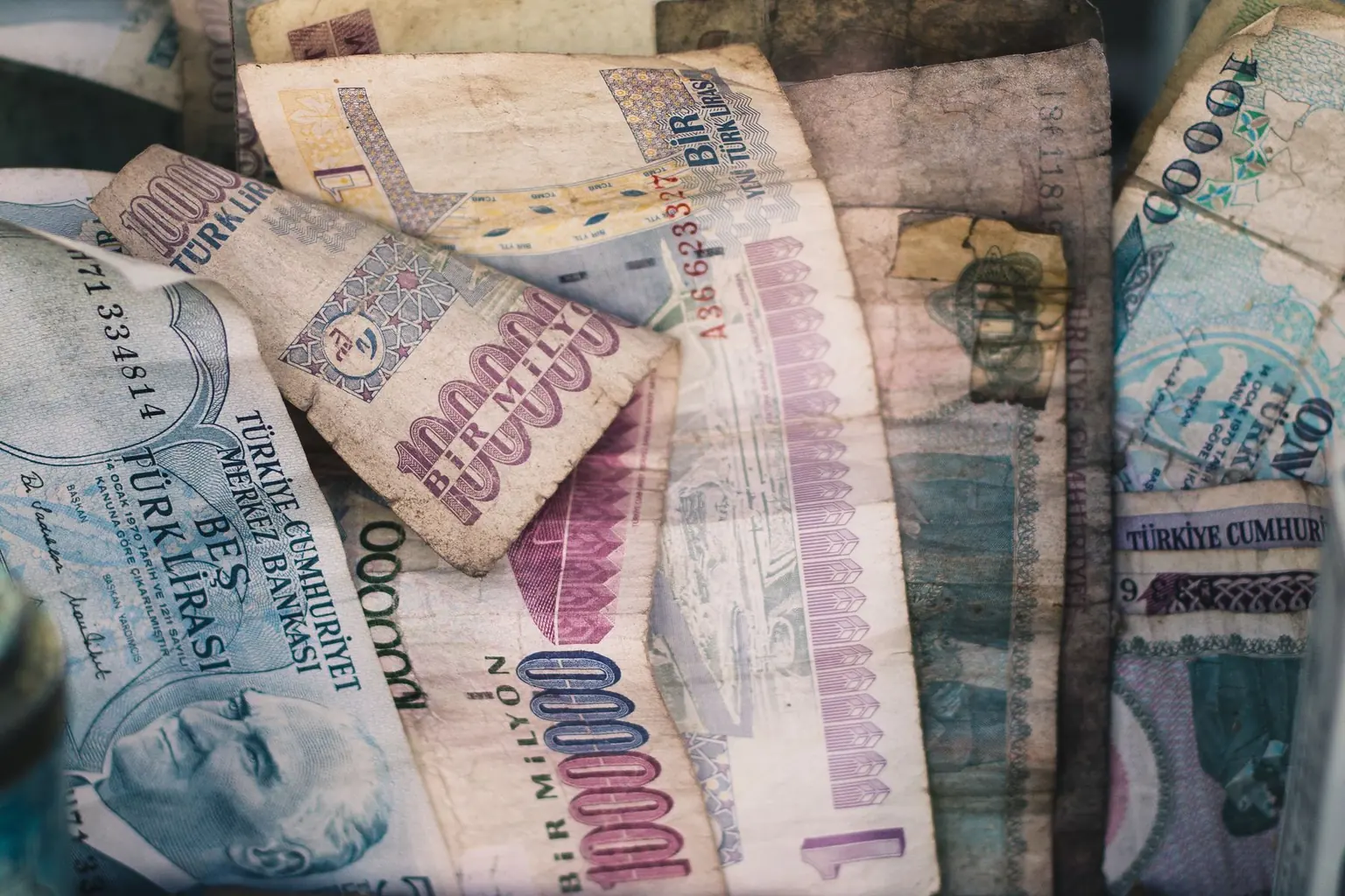 Stacks of old Turkish banknotes and loose coins arranged behind glass in a display